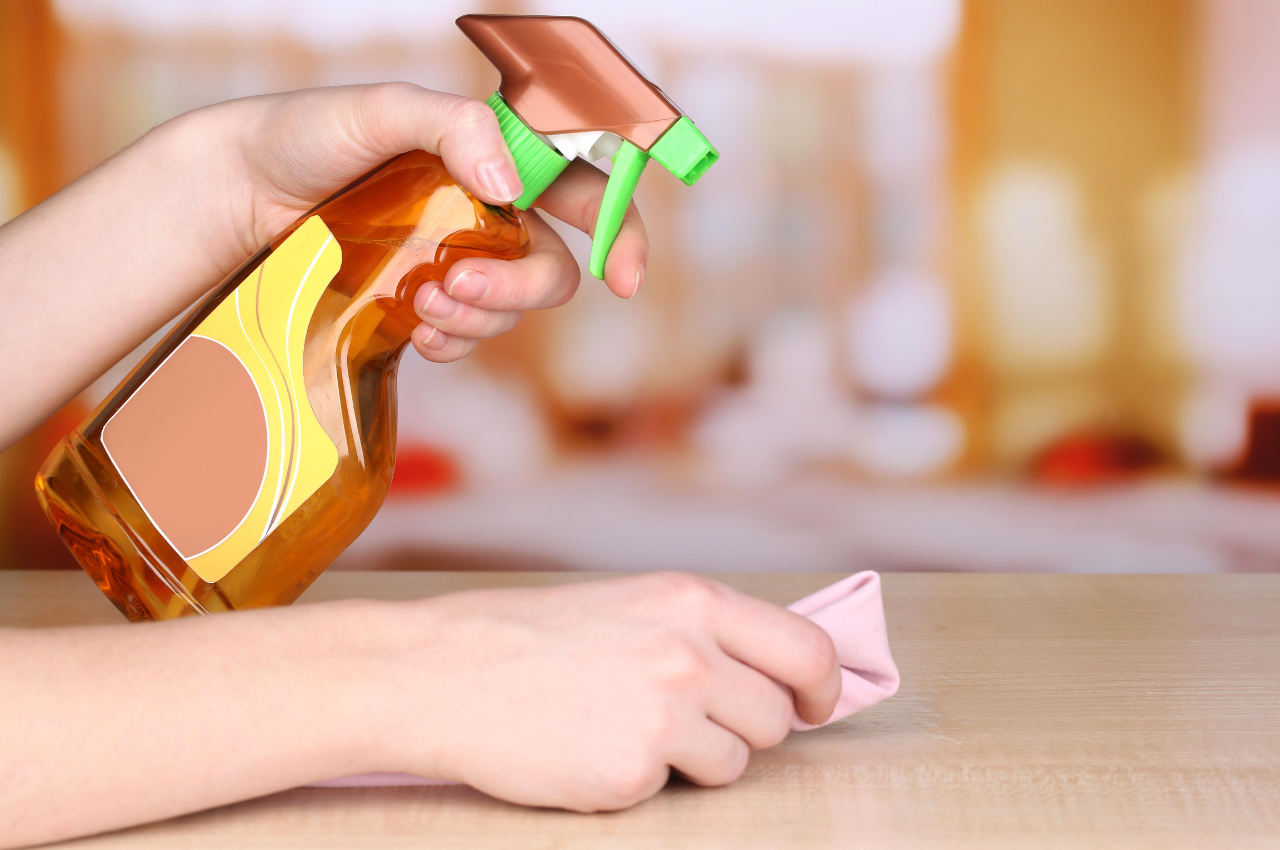 Person holding spray and fabric to clean wood furniture