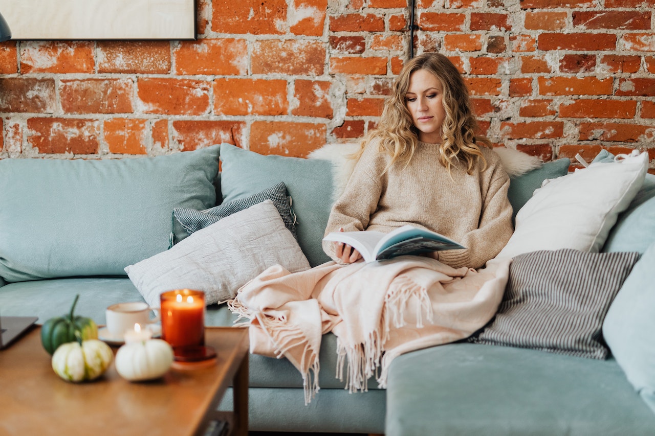 Woman Wearing Brown Sweater Sitting on the Couch