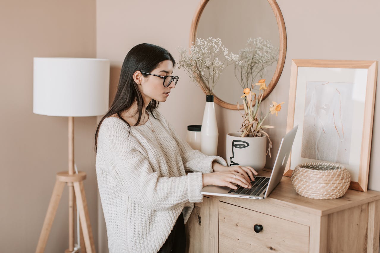 Young woman typing on keyboard of laptop at home