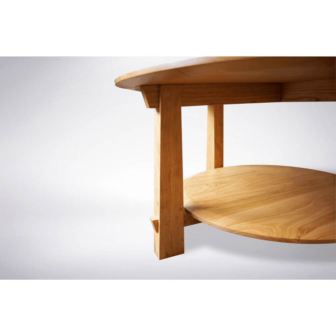 Close-up of the Enso Round Coffee Table by TY Fine Furniture, featuring a solid light wood top, lower circular shelf, and thick sturdy legs with a Japanese-inspired design. Handcrafted in Columbus, OH. Set against a plain white background.