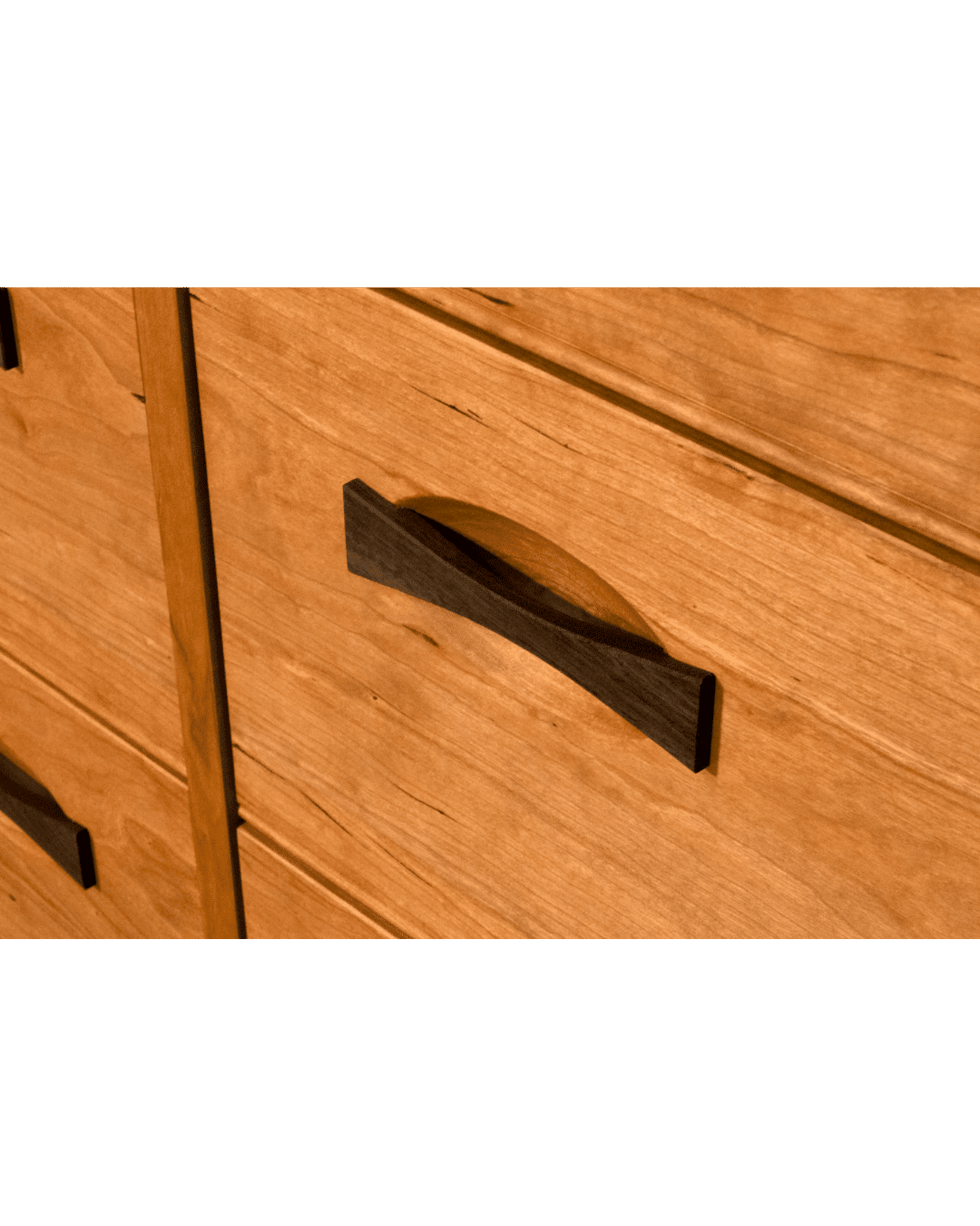 Close-up of the TY Fine Furniture Enso 5-Drawer Upright Dresser in cherry. Handmade from solid wood, it features a warm finish, visible grain, and elegant dark curved handles on each drawer.