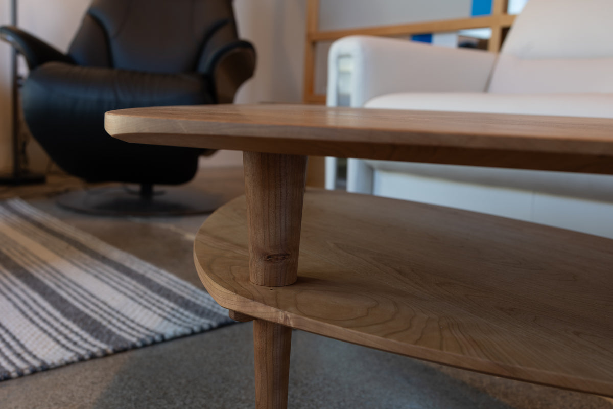 A two-tiered, handmade Solid Cherry Coffee Table - Atomic Collection | TY Fine Furniture featuring a rounded top and a lower shelf.