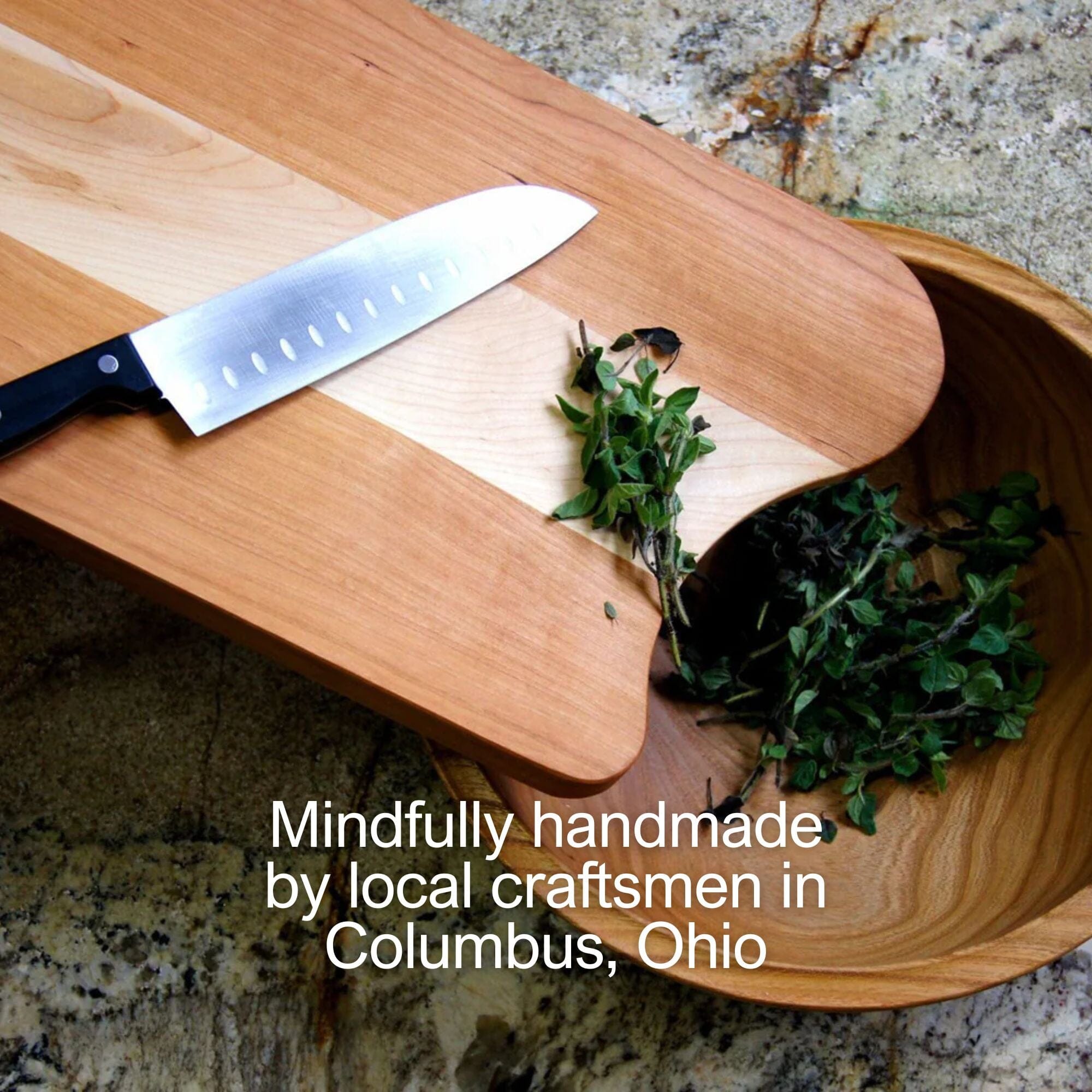 A Butcher Block Cutting Board by TY Fine Furniture sits on a stone countertop with a chef’s knife and herbs, beside a wooden bowl. Text: “Handcrafted in Columbus, Ohio by local artisans.”.