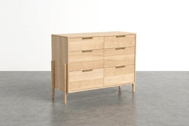 The TY Fine Furniture Solid Maple 6-Drawer Double Bank Dresser from the Apollo Collection, featuring a light wood finish, stands on slim, angled legs atop a gray floor against a plain white wall. This handcrafted dresser showcases simple brass handles and a modern, minimalist design.