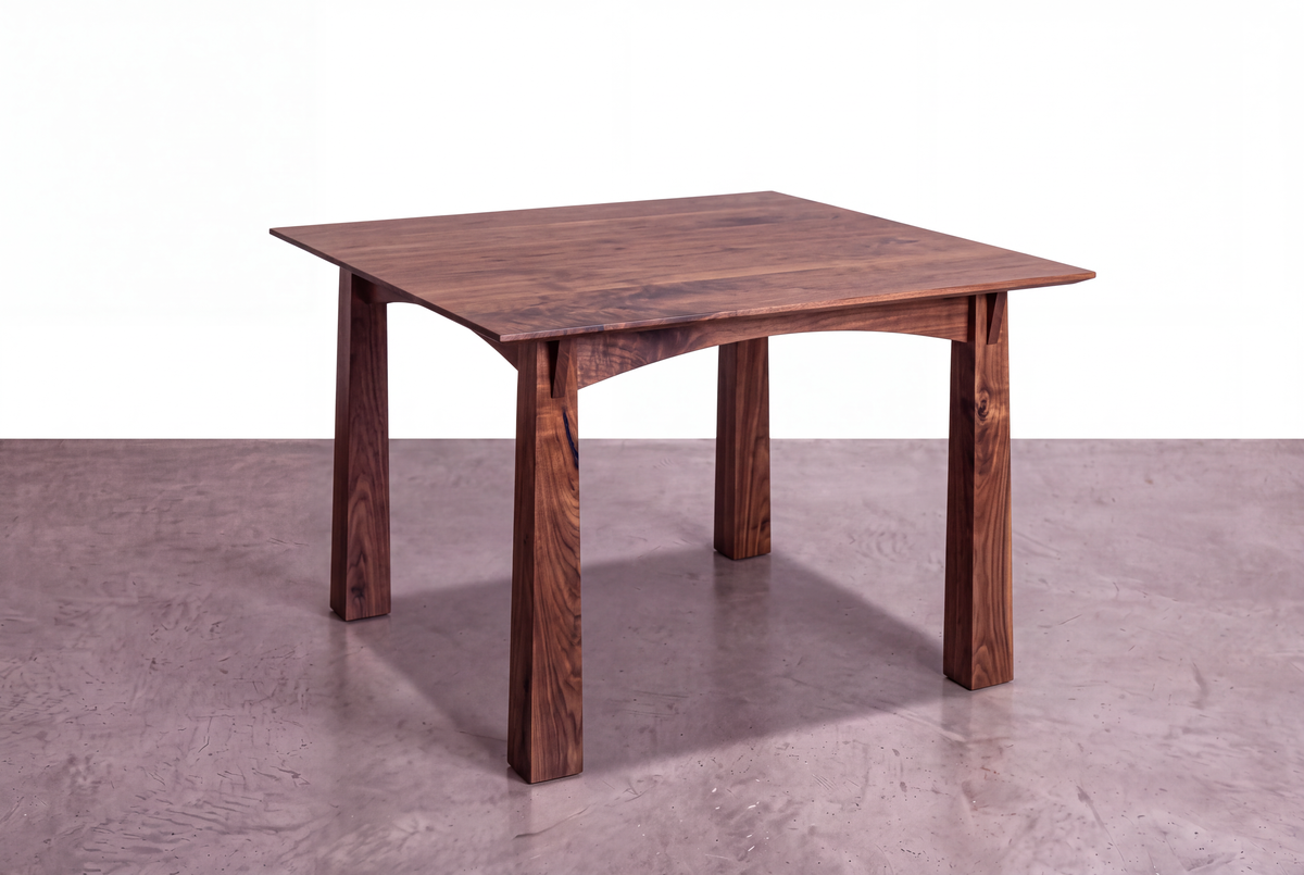 The Solid Cherry Dining Table - Enso Collection | TY Fine Furniture features handcrafted cherry wood, four tapered legs, and elegant arched apron joinery, showcased on a concrete floor with a white background.