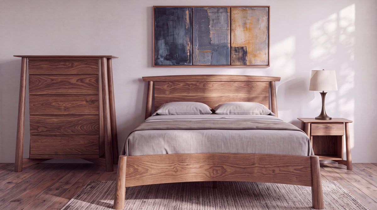 Handcrafted solid wood Sunrise Platform Bed - Walnut with a curved headboard, flanked by a tall dresser and a bedside table with a lamp.