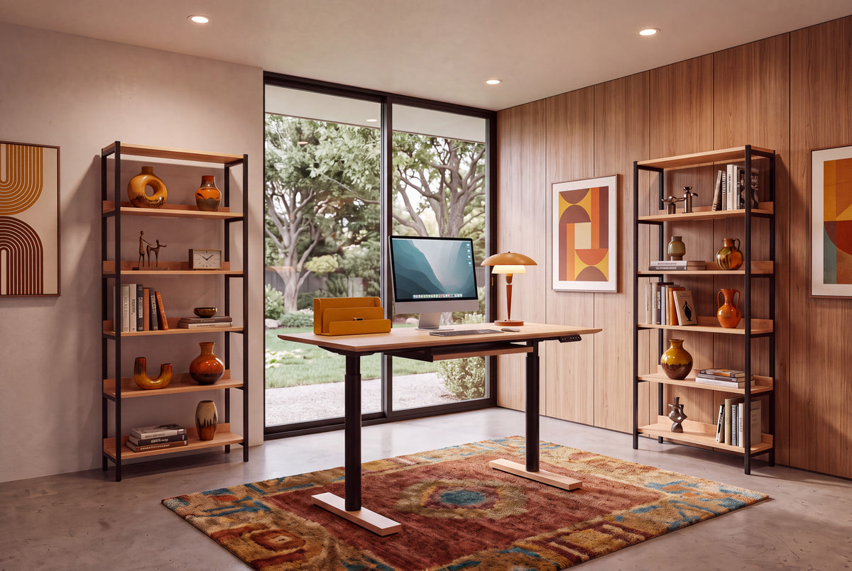 Modern home office with a large desk, computer, and the Solid Cherry Tall Mid-Century Bookcase - Essentials Collection | TY Fine Furniture. Abstract wall art, vases, and a window overlooking a green garden complete the look.