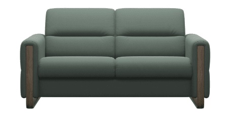 The Stressless Fiona, available as a 3 seater, 2.5 seater, 2 seater, or 1 seater, is a modern green sofa with wooden armrests and a plush cushioned backrest by Stressless, blending style and comfort against a white background.