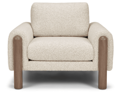 The American Leather Revie Chair by American Leather features a textured cream fabric, high-density foam seat, wide cushioned backrest, and cylindrical solid walnut wood legs and armrests, shown from the front.