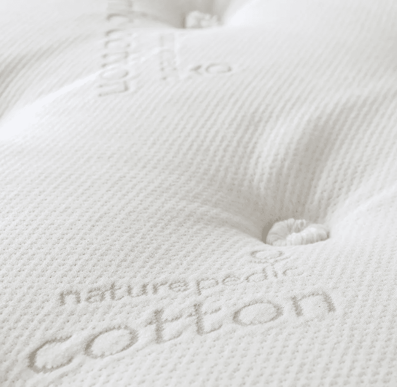 Close-up of the Naturepedic Concerto Plush Pillow Top Mattress, showing its textured white organic surface with "naturepedic cotton" stitched into the fabric and detailed tufted button accents.