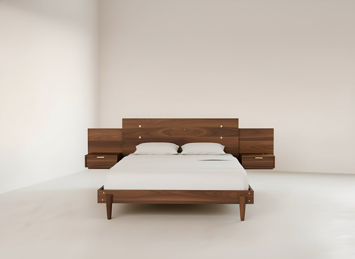 A minimalist bedroom featuring the Apollo Platform Bed with Integrated Tables in walnut by TY Fine Furniture, topped with two white pillows, crisp white bedding, and matching built-in wooden nightstands against a light wall.