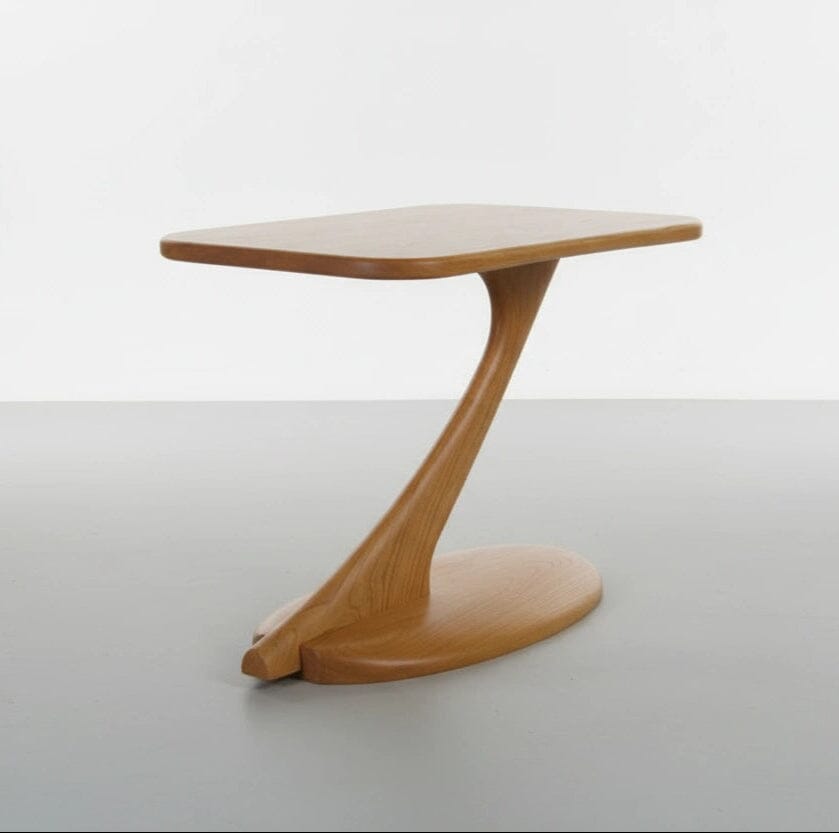 The Cantilever Side Table Solid Wood Handmade - Cherry by TY Fine Furniture features a modern artisan-crafted design with a curved, asymmetrical base and rectangular top, showcased against a plain white background.