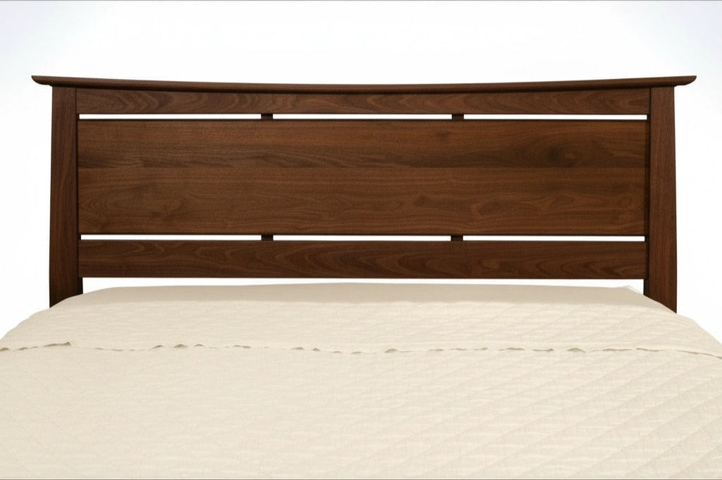 The Enso Platform Bed Walnut by TY Fine Furniture features a wooden headboard with horizontal slats, paired with a cream, textured quilted bedspread. The Japanese-inspired frame is set against a plain white background.