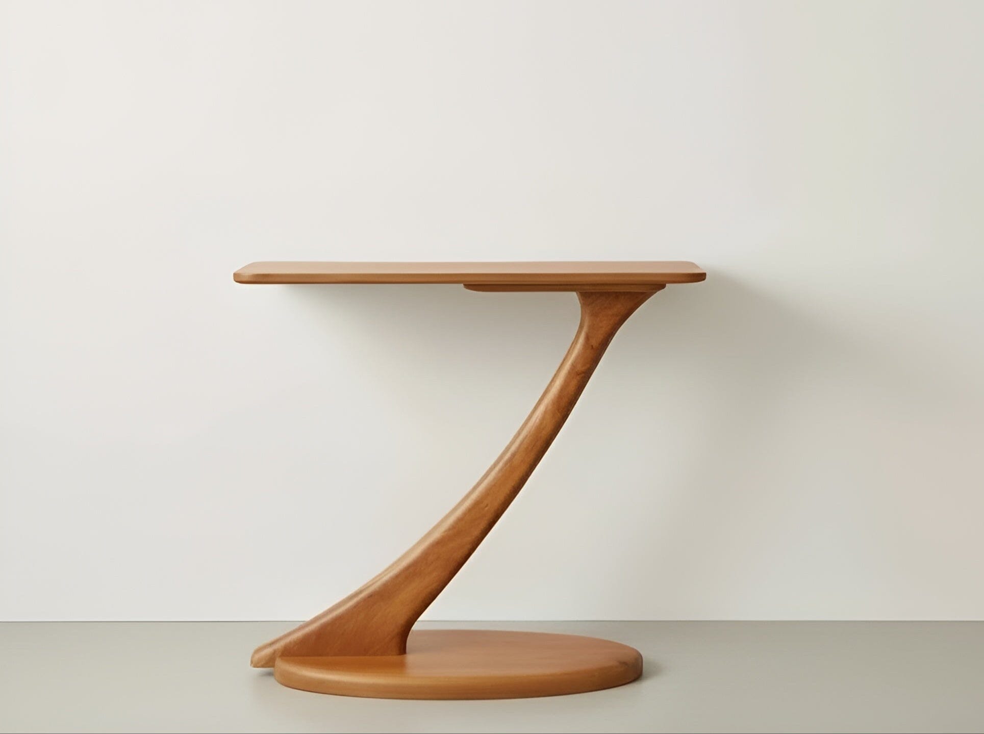 The Cantilever Console Table in cherry by TY Fine Furniture features a modern, Z-shaped solid wood base and stands against a plain white wall and light floor. Made in the USA.