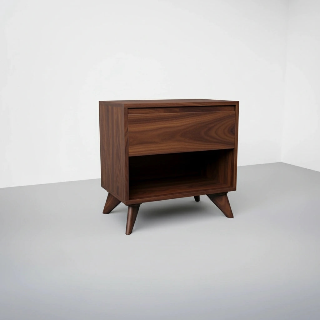 The Modern Cube Side Table - Walnut by TY Fine Furniture features solid wood construction, angled legs, a push-to-open top drawer, and an open lower shelf—shown against a plain white wall and gray floor.