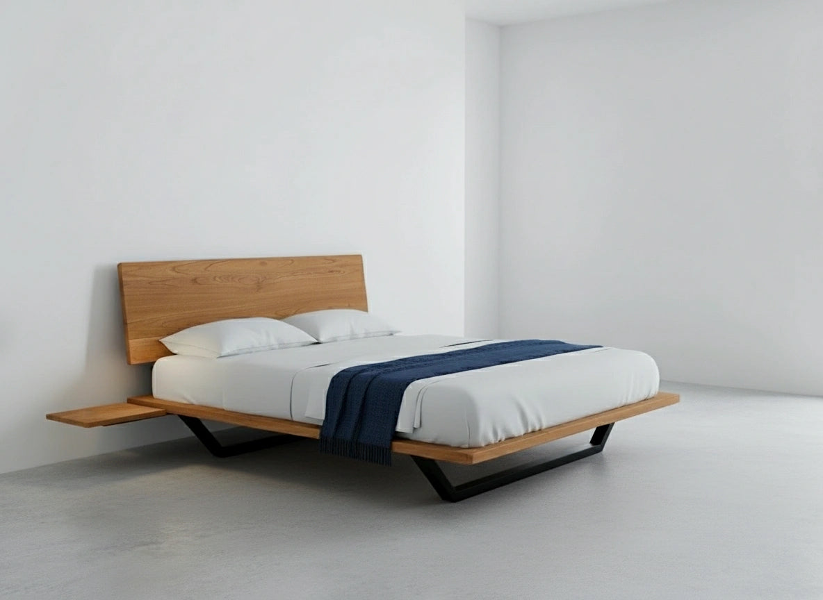 The Nelson Solid Wood Platform Bed Frame by TY Fine Furniture, handmade in the USA from cherry wood, stands on angled legs with a light headboard, dressed in white bedding and a dark blue throw, set in a bright room with white walls and floor.