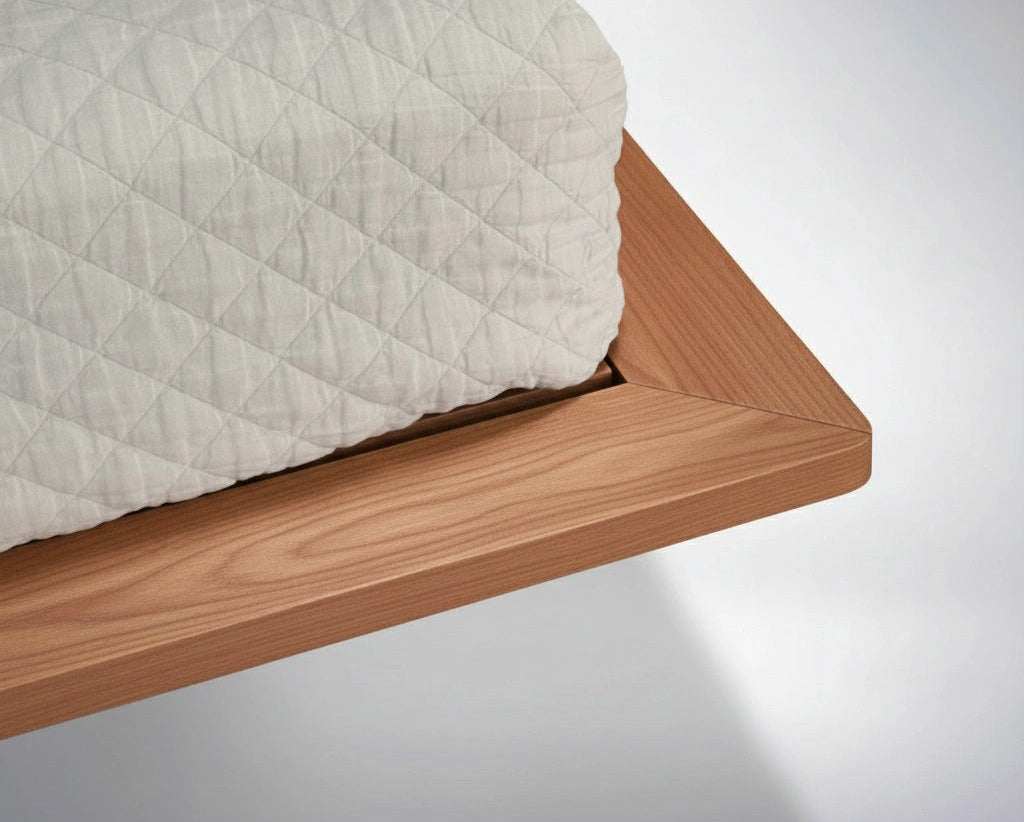 A close-up of the Nelson Solid Wood Platform Bed Frame by TY Fine Furniture, handmade in cherry wood with a smooth, natural finish, topped with a light-colored mattress featuring a diamond-patterned cover.