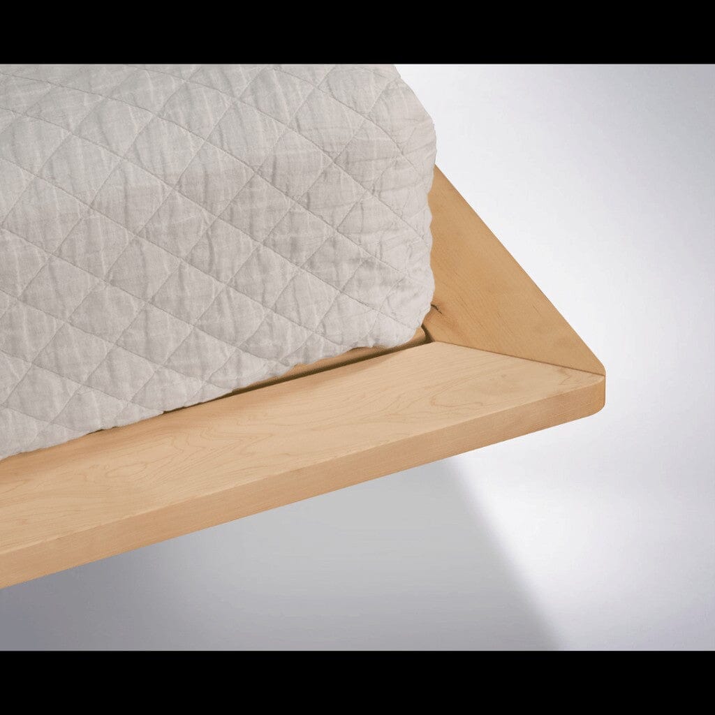 Close-up of the Atomic Platform Bed by TY Fine Furniture, showcasing its clean lines, smooth finish, and expert craftsmanship in solid maple, topped with a mattress in white quilted fabric.