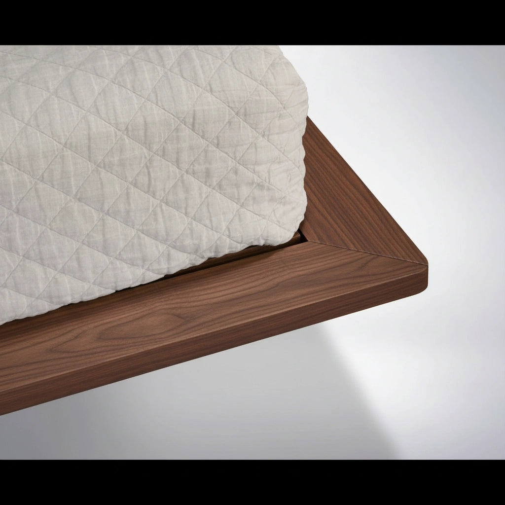 A close-up of the Atomic Platform Bed in solid walnut by TY Fine Furniture shows a quilted white mattress on its smooth, angled edges, reflecting classic mid-century modern design.