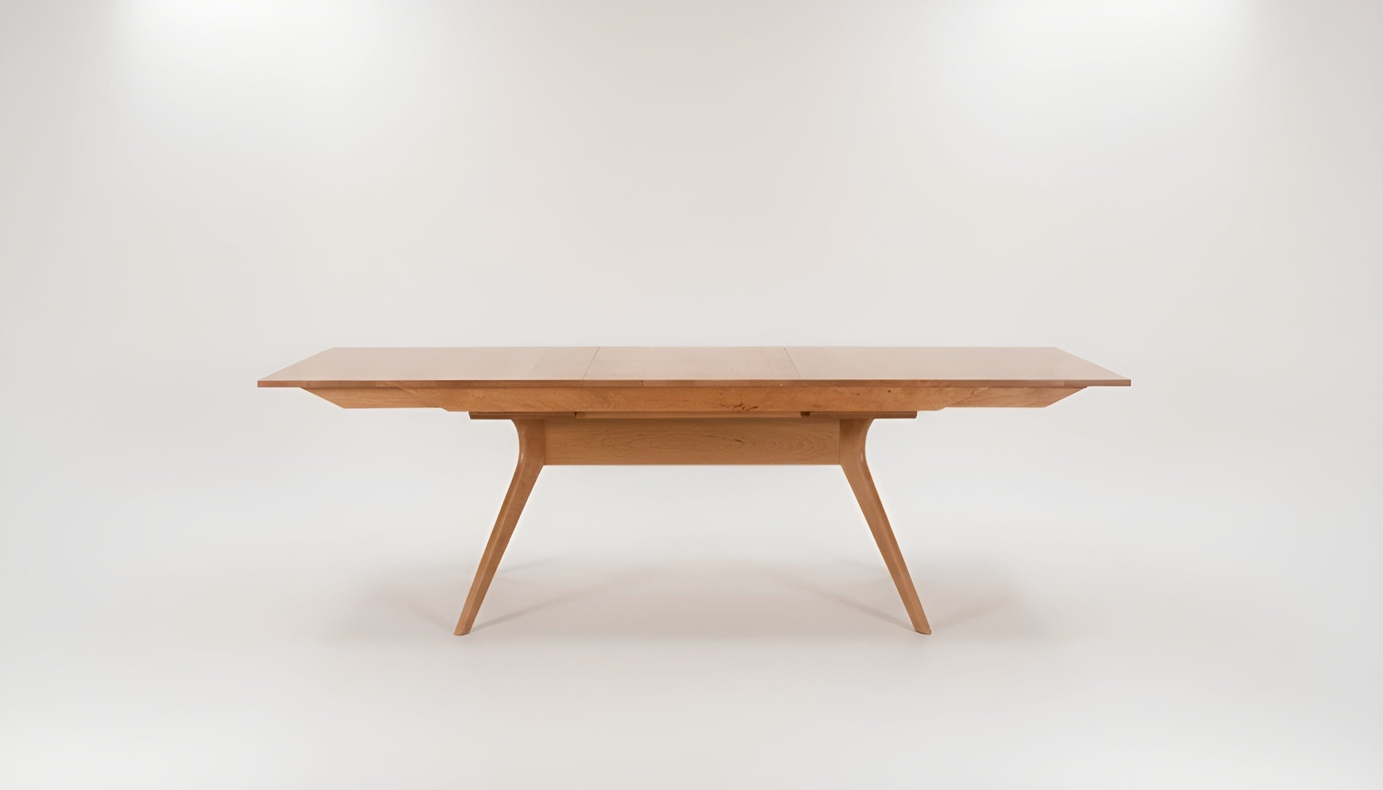 The Strata Extendable Dining Table - Cherry by TY Fine Furniture features a sleek solid wood design with angled legs and a smooth surface, set against a plain white background—ideal for modern, minimalist interiors.