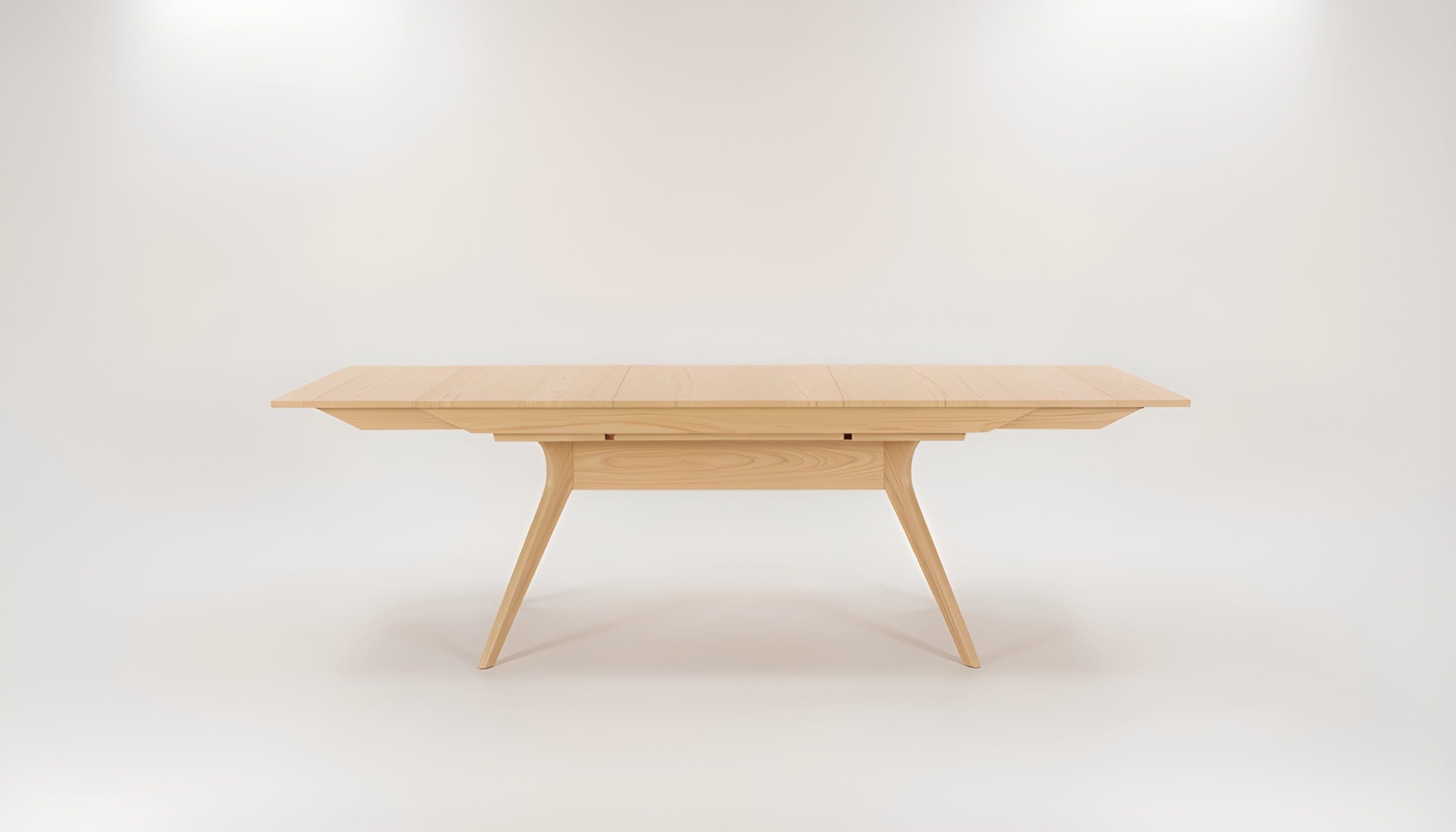 The Strata Extendable Dining Table by TY Fine Furniture features a modern rectangular solid white oak top with angled legs and a light finish, displayed against a plain white background.