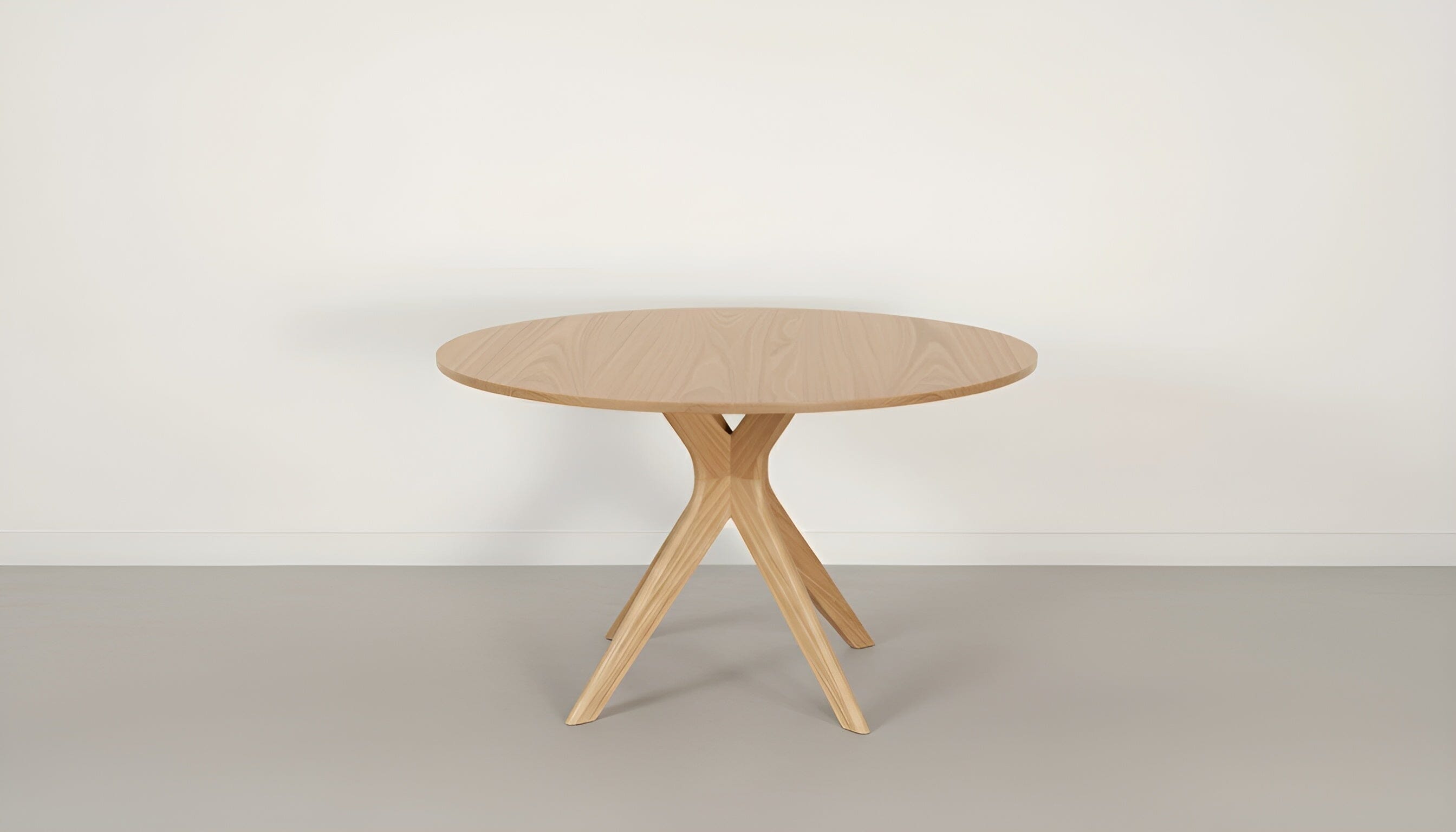 The TY Fine Furniture Strata Round Dining Table - Solid Wood | Columbus features a light finish and three angled legs, standing against a plain white wall and gray floor.