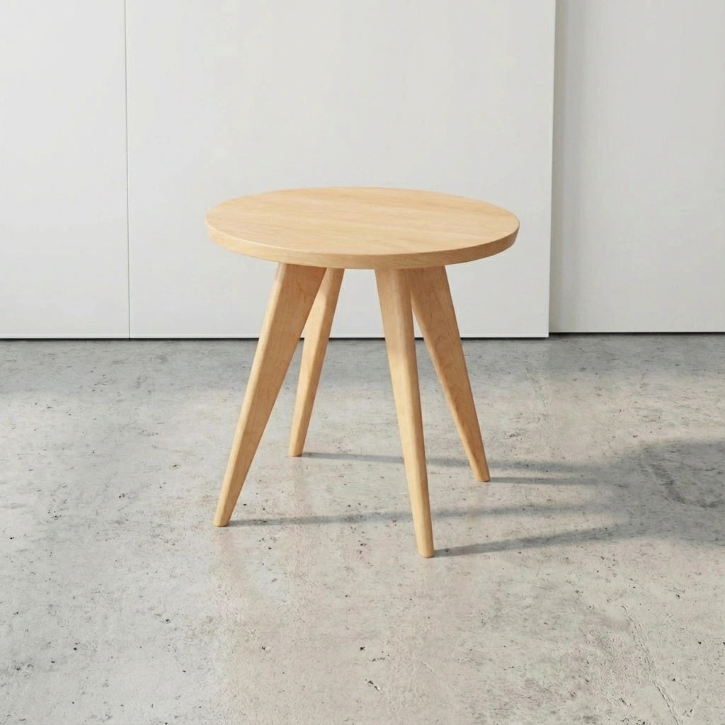 The Essentials Solid Wood Round Side Table by TY Fine Furniture, handcrafted in maple in Columbus, Ohio, features a sleek round design with three angled legs—perfect for adding Mid-Century Modern flair to any space.