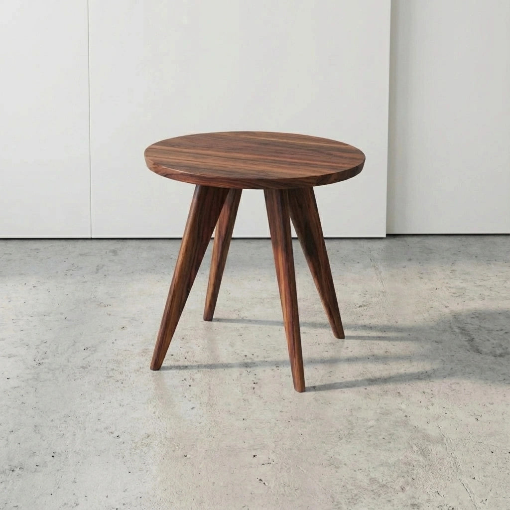 The Essentials Solid Wood Round Side Table by TY Fine Furniture, handcrafted in Columbus, Ohio from white oak, features a round top and three angled legs—showcasing a mid-century modern style against a plain white wall.