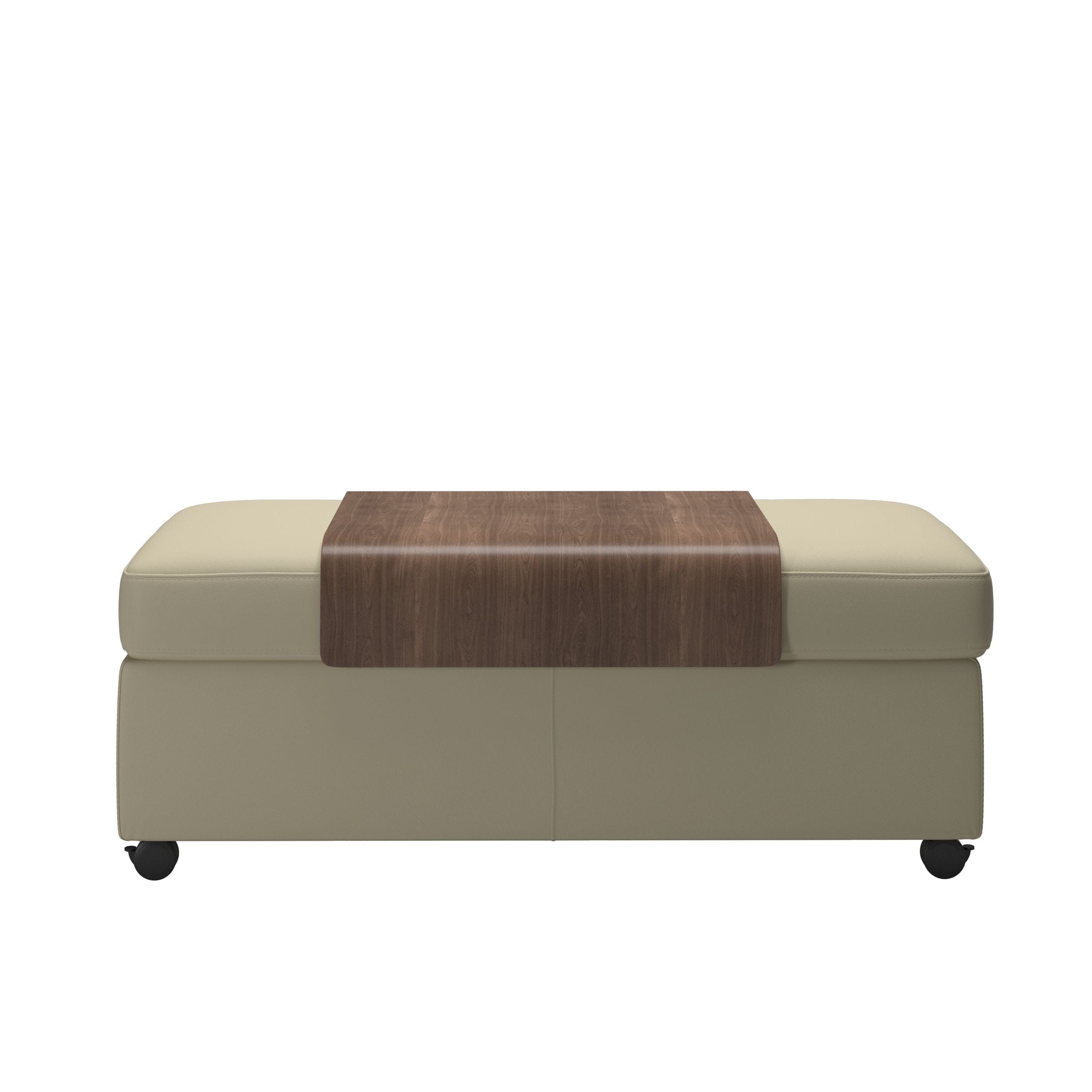The Stressless Double Ottoman Coffee Table by Stressless is a rectangular beige ottoman with a smooth surface and small black wheels, topped with a wooden tray at its center, shown against a plain white background.