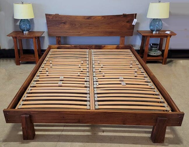 A TY Sleep EuroSlat Foundation bed frame for lower back support is flanked by two matching nightstands, each topped with a blue glass lamp and white shade. The bed does not include a mattress.