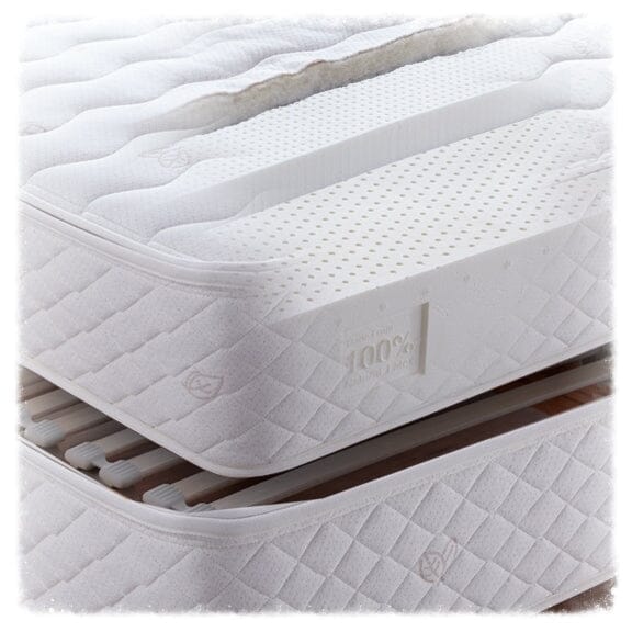 A close-up of the TY Sleep 7 Zone Latex mattress by TY Sleep shows its perforated, 100% natural latex layers with a 7-zone ergonomic design, partly cut away to reveal the interior, resting on a slatted box spring.