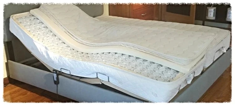 The TY Sleep Riviera by TY Sleep is an adjustable bed with a split mattress, shown partially raised for articulated back support. Head and foot sections adjust independently via a wired remote attached to the bed frame.
