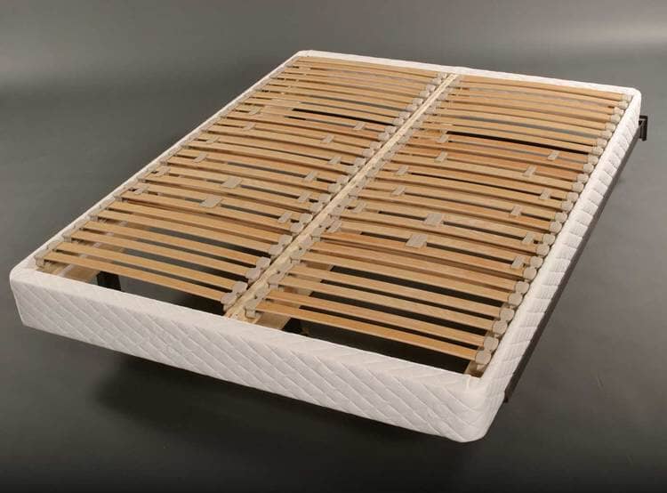 The TY Sleep EuroSlat Foundation by TY Sleep is a bed frame with a white fabric base and sturdy wooden slats, uniquely designed to support your mattress and enhance lower back support. Shown against a dark, plain background.