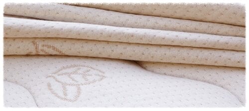Close-up of beige, quilted fabric with dotted patterns and embroidered leaf design on the TY Sleep Luxury Mattress Topper by TY Sleep—Columbus, OH—evoking comfort and enhanced sleep quality.