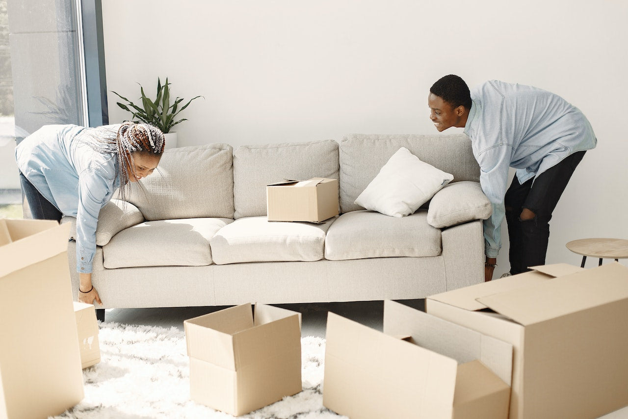 A Man and a Woman Lifting a Couch Together