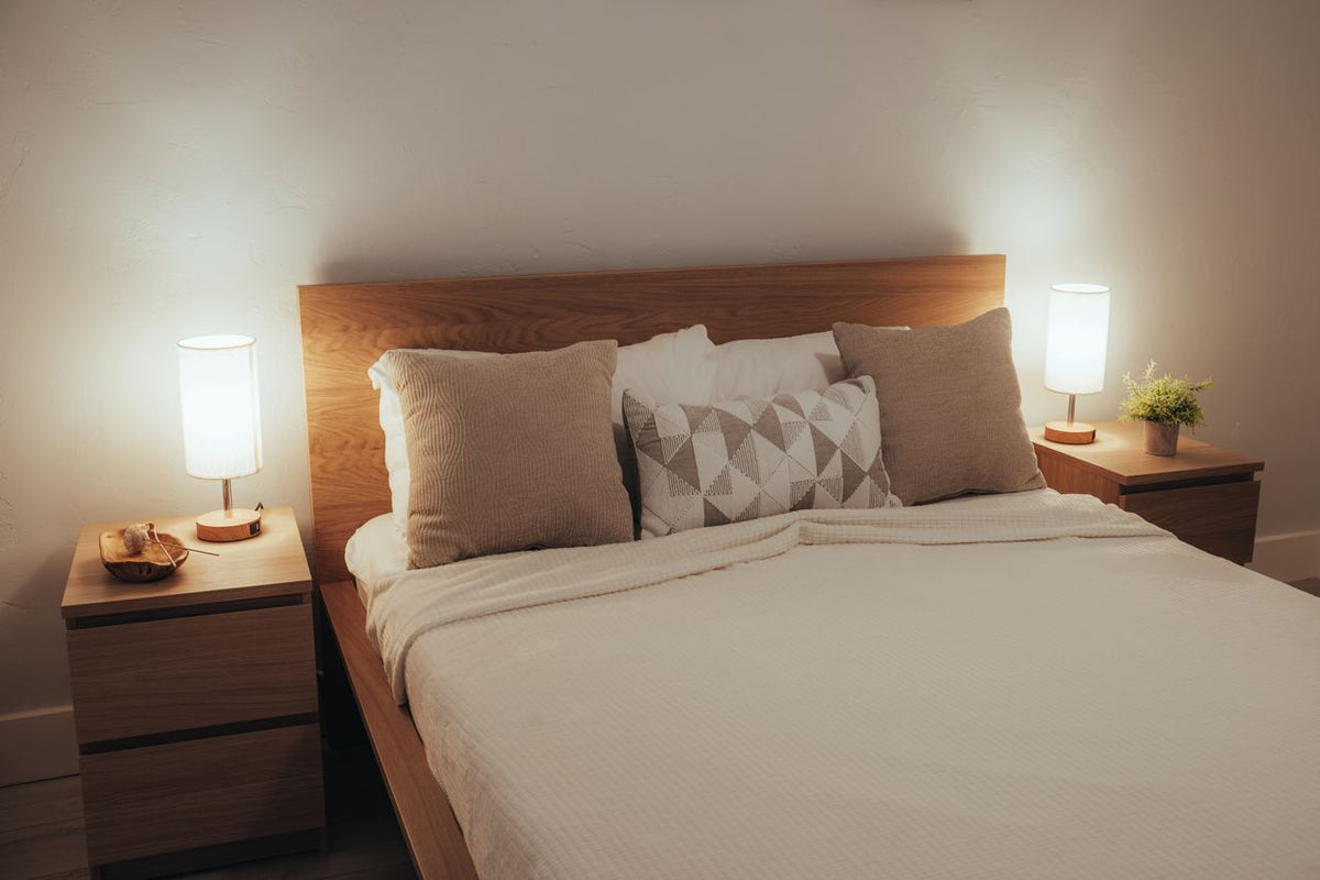 A minimalist bedroom featuring soft lighting, modern furniture, and cozy bedding