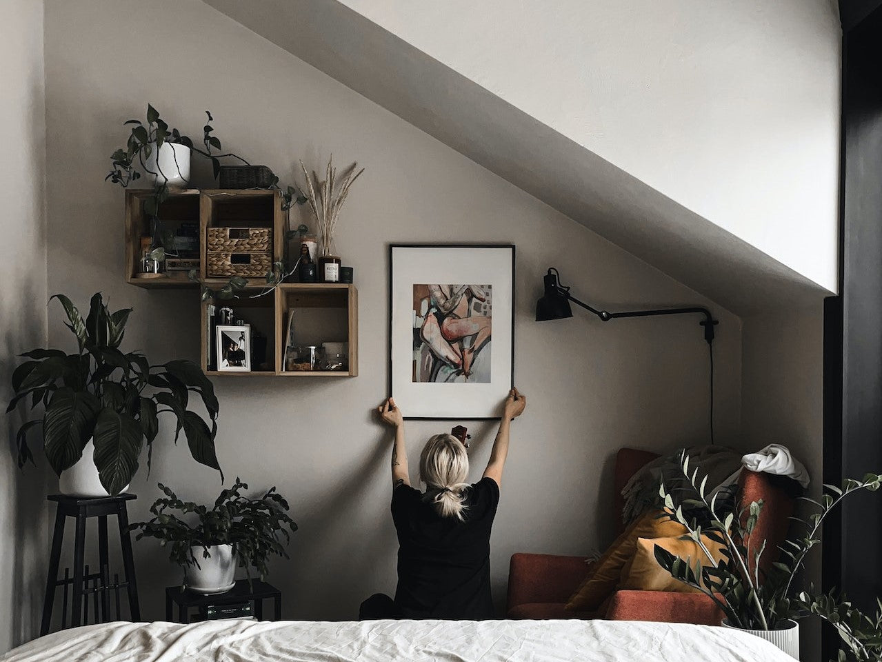 Woman Hanging a Painting in her Bedroom