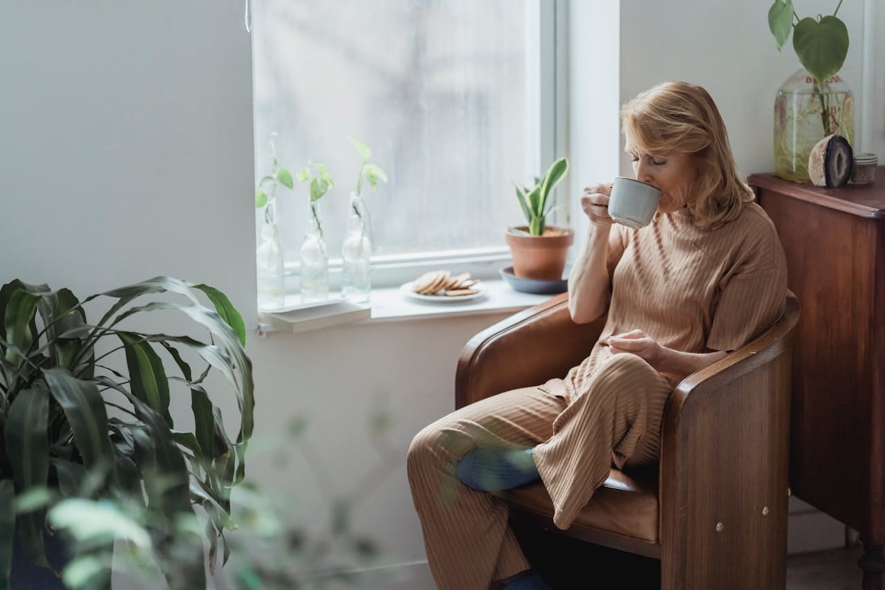 Woman Sitting in an Armchair and Drinking Coffee
