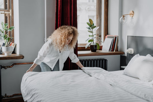 Woman in White Long Sleeve Shirt Arranging Bed