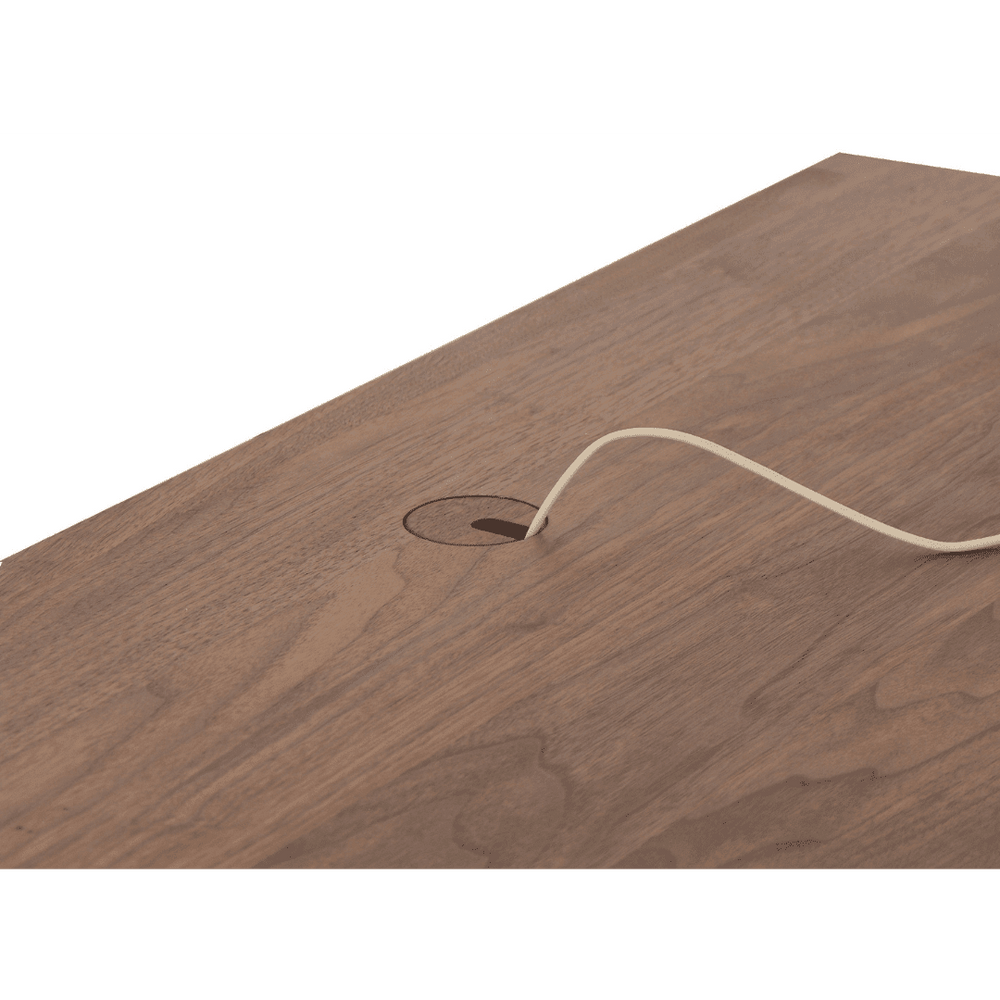 A close-up of a brown wooden desk with a cable management hole