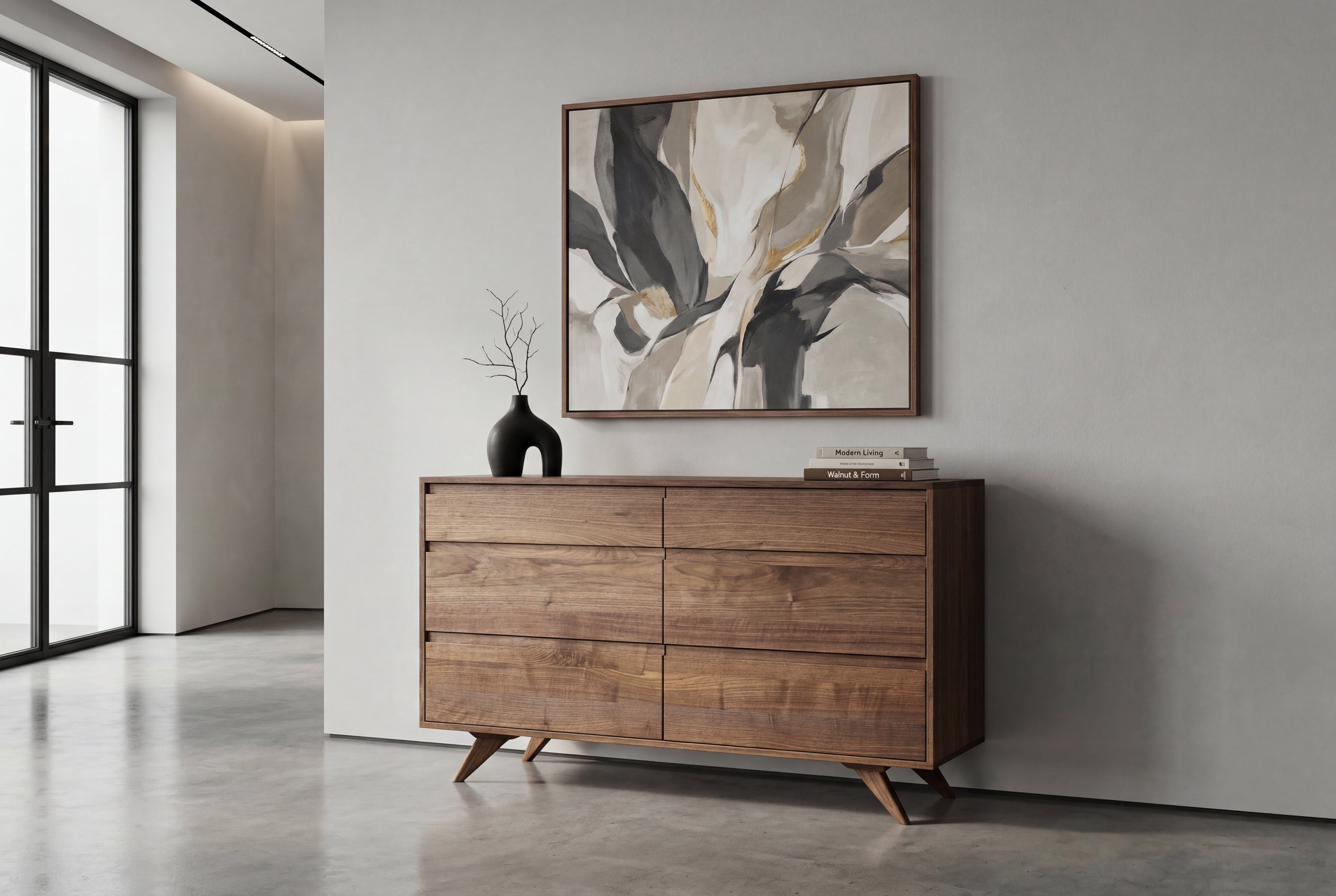 A Solid Maple 6-Drawer Double Bank Dresser from TY Fine Furniture’s Modern Collection, featuring classic Mid-Century angled legs, sits against a light wall. On top are two stacked books and a black vase holding a slender branch, while an abstract painting in neutral tones hangs above.