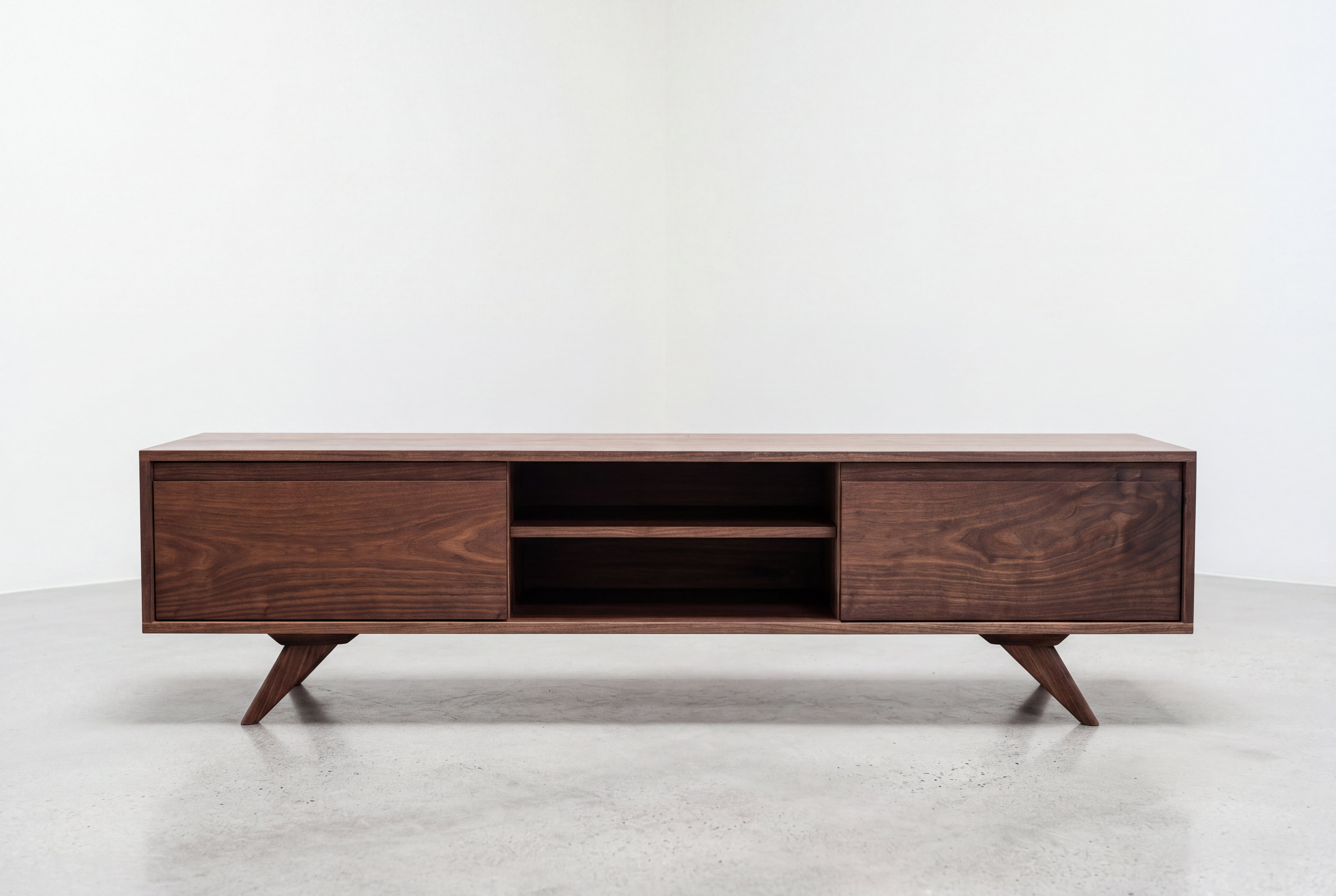 The Modern Entertainment Console with Drawers by TY Fine Furniture is a solid wood TV stand featuring angled legs, two closed cabinets on each side for generous storage, and open central shelves—all showcased against a plain white background.