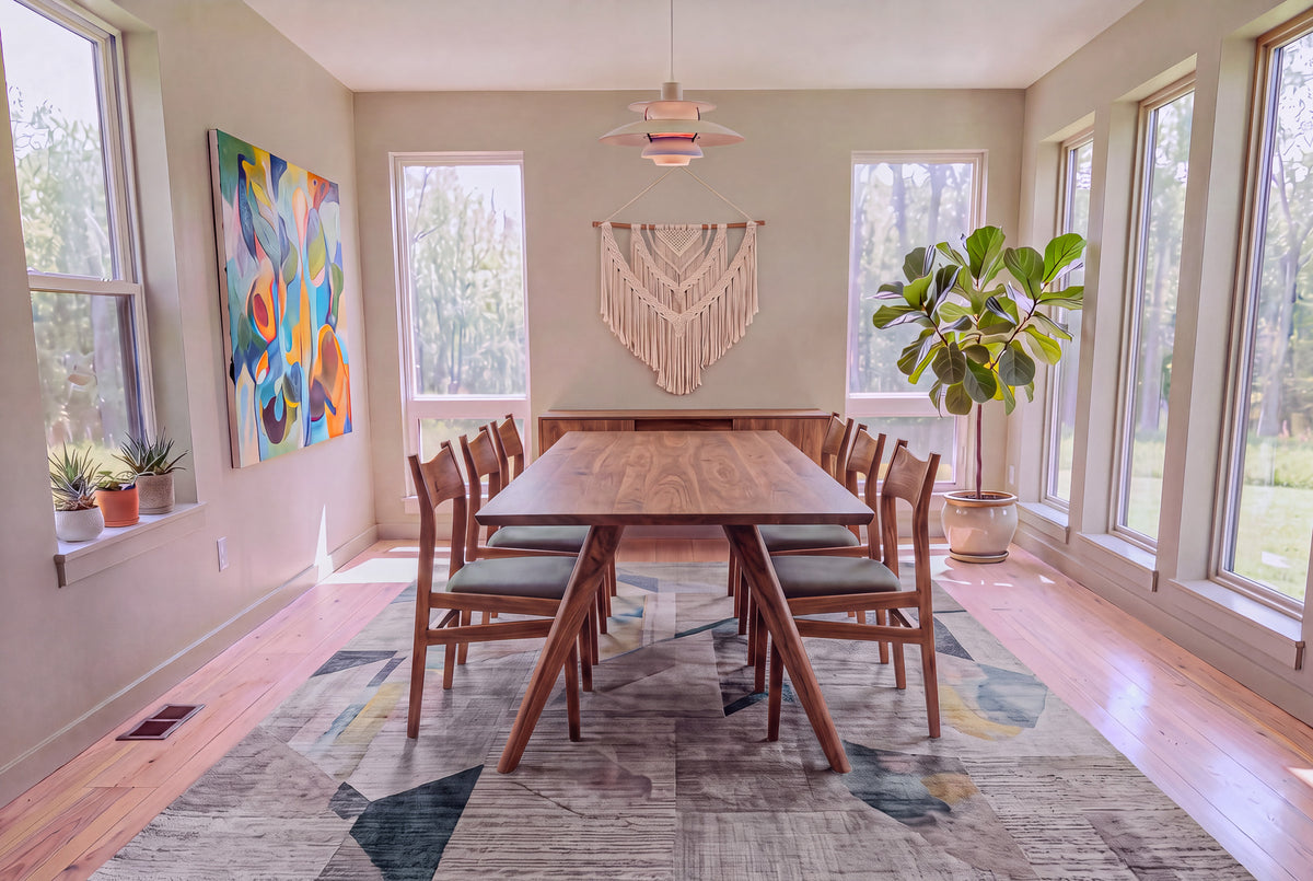A bright dining room featuring the Solid Walnut Dining Table from TY Fine Furniture’s Essentials Collection with six chairs, abstract wall art, macramé decor, potted plants, and large windows letting in natural light.