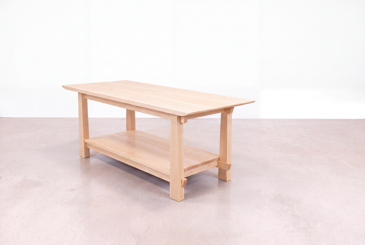 A Solid Maple Horizon Coffee Table from the Horizon Collection by TY Fine Furniture, crafted in the tradition of Japanese craftsmanship, features a lower shelf and sits gracefully on a smooth, light-colored floor against a plain white background.