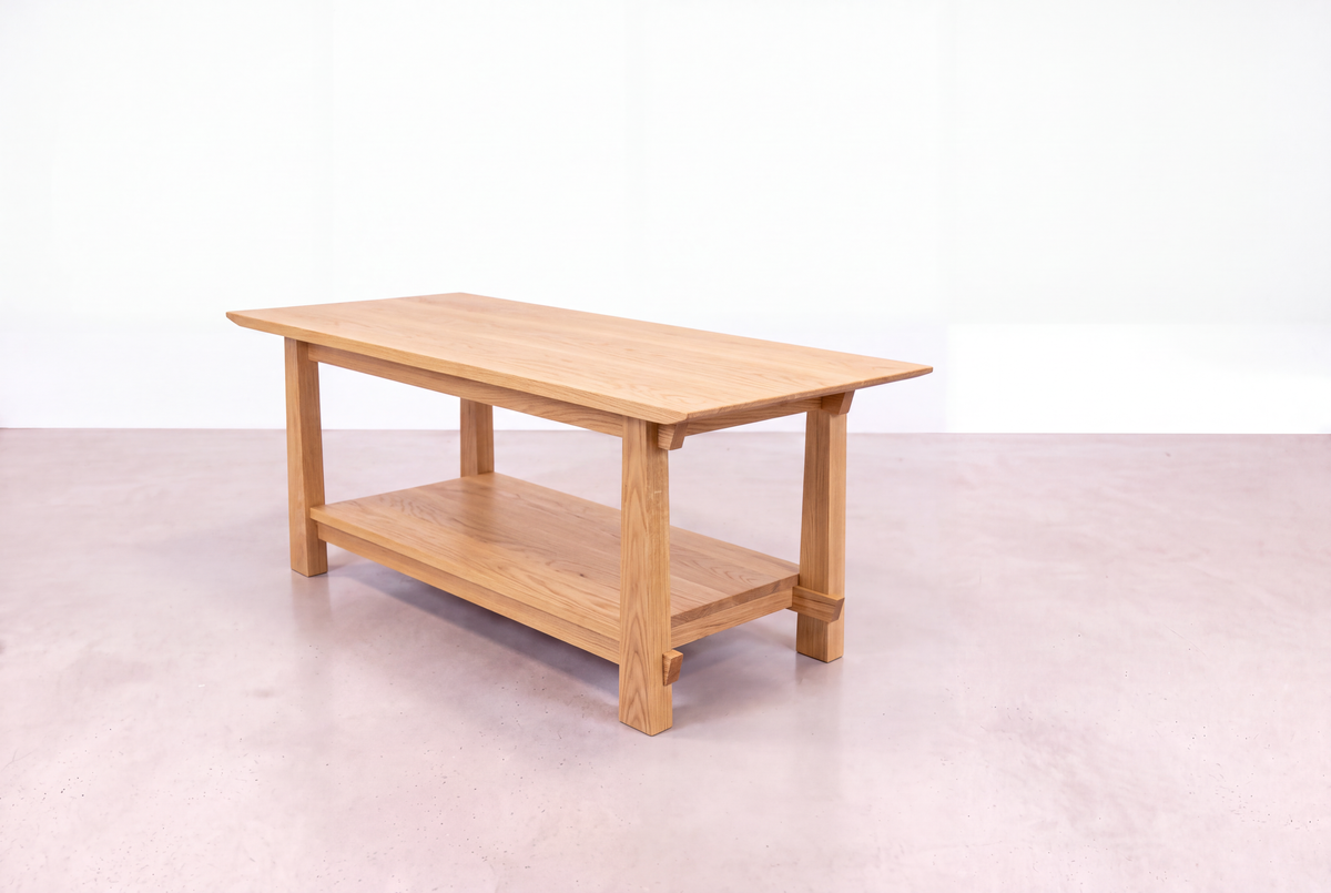 The Solid White Oak Horizon Coffee Table from the Horizon Collection by TY Fine Furniture, expertly crafted with Japanese woodworking techniques, showcases a rectangular profile and a practical lower shelf. Set on a smooth, light pink floor against a white background, this piece is an ideal choice for modern interiors.