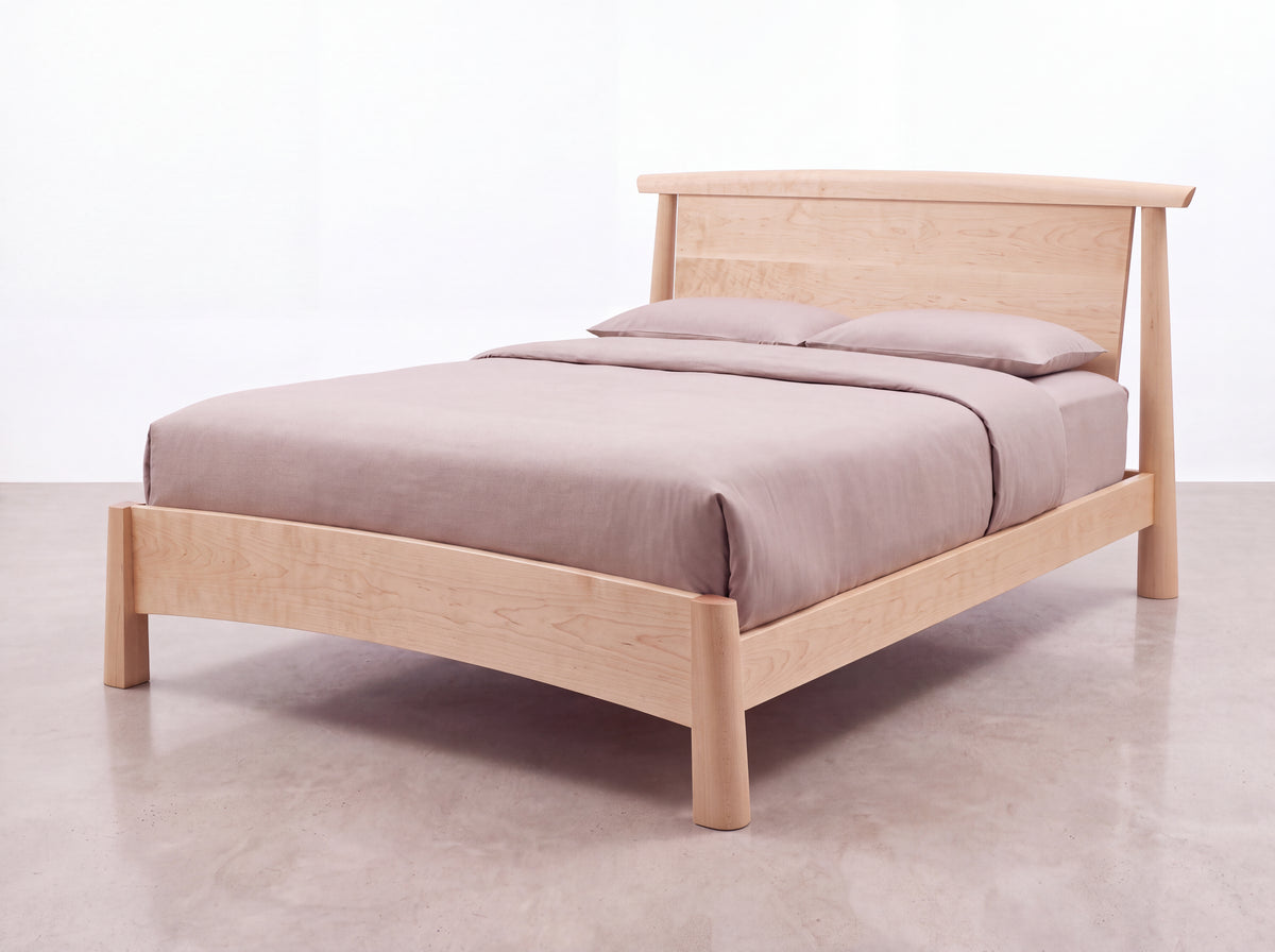 Sunrise Platform Bed - Maple featuring a handcrafted design with a curved headboard and light brown bedding.