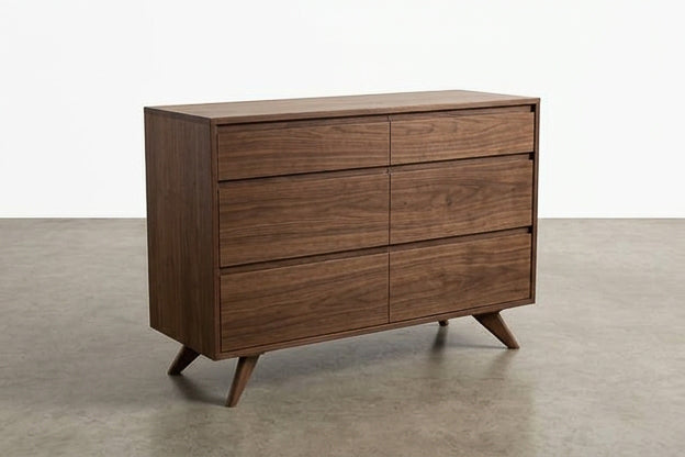 The Solid Walnut 6-Drawer Double Bank Dresser from TY Fine Furniture’s Modern Collection is a handcrafted mid-century modern piece featuring six spacious drawers and angled legs, shown here on a concrete floor with a plain white wall backdrop.