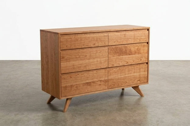 A Solid Cherry 4-Drawer Double Bank Dresser from the Modern Collection by TY Fine Furniture, showcasing clean lines and a natural cherry finish, stands on a plain concrete floor against a white background—a perfect example of handcrafted furniture.