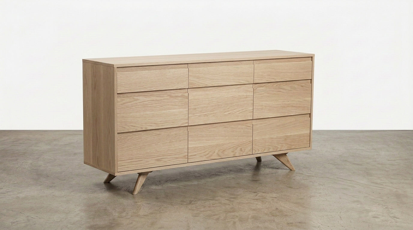 Introducing the Solid White Oak 9-Drawer Triple Bank Dresser from the Modern Collection by TY Fine Furniture—a meticulously handcrafted piece featuring nine spacious drawers and elegantly angled legs, beautifully displayed on a concrete floor against a plain white wall.