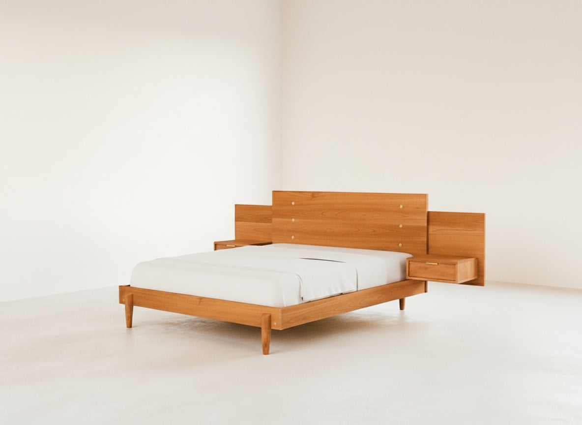 The Apollo Platform Bed with Integrated Tables Cherry by TY Fine Furniture, handcrafted from cherry wood, features a wide headboard with built-in floating nightstands and drawers. It is pictured in a bright, empty room with white walls and floor.